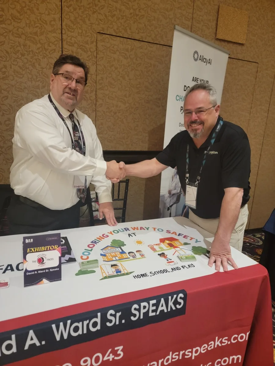 David A. Ward Sr. shaking hands with an attendee at his safety book display table